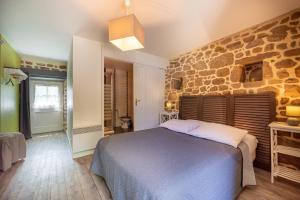 a bedroom with a stone wall and a bed at Gîtes Ker Mané in Erdeven