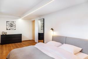 a white bedroom with a bed and a dresser at Chalet Flocke Appart Schneehase in Sankt Anton am Arlberg