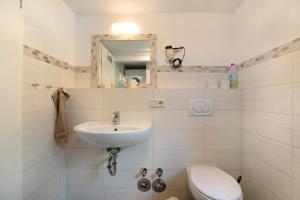 a white bathroom with a sink and a toilet at Ketelsens Ferienwohnung in Bohmstedt +13 photos