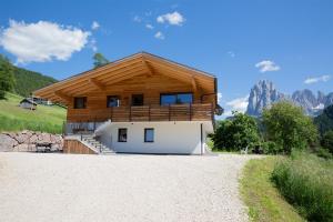 a house with a wooden roof on a mountain at Apt Lara Siela in Ortisei