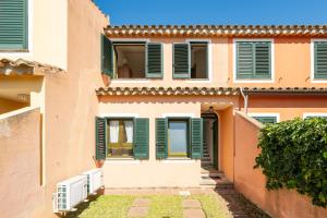 a building with green shutters and a yard at Villetta Stella in Chia