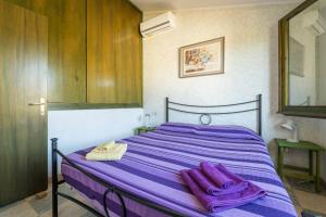 a bed with purple sheets and towels on it at Villetta Stella in Chia