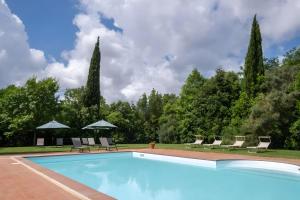 a swimming pool in a yard with chairs and umbrellas at Rosaspina - Appartamento 7 in Capalbio