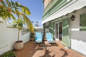 a patio with two blue chairs and a palm tree at Villa Spinnaker Playa in Puerto de Santiago