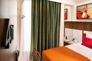 a hotel room with a bed and a green curtain at Hôtel Eiffel Turenne in Paris