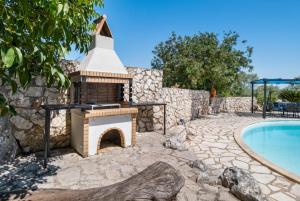 a brick fireplace next to a swimming pool at Villa Jimmy's Katomeri 3 in Meganisi