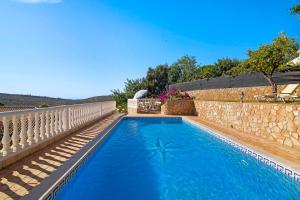 a swimming pool next to a stone wall with a blue pool at Villa Isabel in Loulé