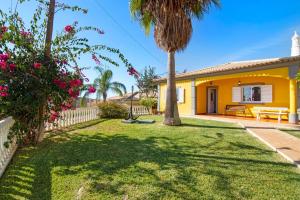 a yellow house with a palm tree in a yard at Villa Isabel in Loulé