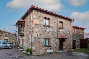 a stone building with a car parked in front of it at La Plazuela I in Pereña