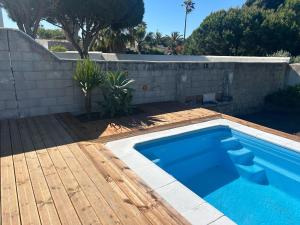 a swimming pool with a wooden deck next to a wall at Casa Luna in Los Caños de Meca