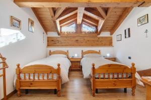 two beds in a room with a wooden ceiling at Ginepro Casa Vacanze in Madesimo