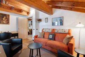 a living room with an orange couch and tables at Ginepro Casa Vacanze in Madesimo