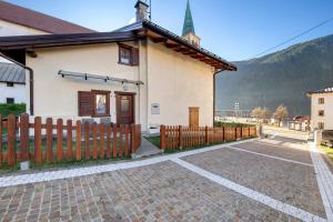 a small house with a wooden fence next to a road at Villa Maria Auronzo in Auronzo di Cadore