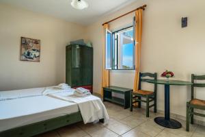 a bedroom with a bed and a table and a window at Anemona studio E in Kefallonia
