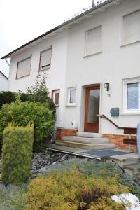 a white house with a front door and some bushes at Apartment Gartenblick in Korbach