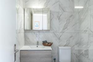a white bathroom with a sink and a mirror at Frantzis studio 4 in Páloi