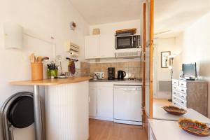 a small kitchen with white cabinets and a microwave at Studio Sanary in Sanary-sur-Mer +14 photos