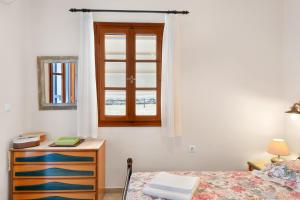 a bedroom with a bed and a dresser and a window at Argyris comfy apartment in Kithnos