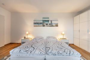a white bedroom with a bed with two lamps at Ferienhaus Dunklau in Wesselburen