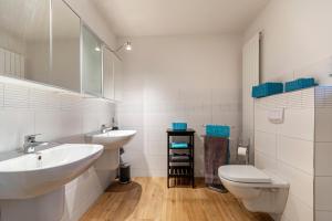 a white bathroom with two sinks and a toilet at Ferienhaus Dunklau in Wesselburen +16 photos