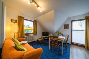 a living room with an orange couch and a table at Olde Toornblick in Borkum +9 photos