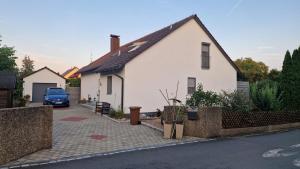 a white house with a blue truck parked in the driveway at Ferienwohnung Bauer in Puschendorf