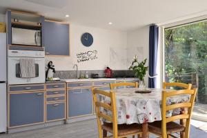 a kitchen with blue cabinets and a table with chairs at Au Fil De L'eau in Chein-Dessus