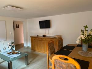 a living room with a table and a tv on the wall at Ferienwohnung Bauer in Puschendorf