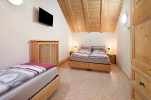 a bedroom with two beds and a flat screen tv at Appartamento Gemma in Livigno