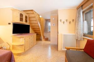a living room with a television and a staircase at Appartamento Gemma in Livigno