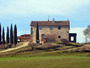 an old stone house on a hill with trees at Podere Spagliarda in San Quirico dʼOrcia
