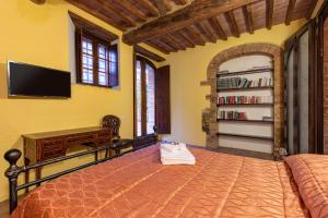 a bedroom with a bed and a flat screen tv at Podere Spagliarda in San Quirico dʼOrcia