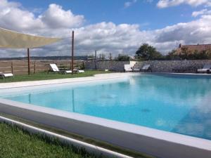 a large blue swimming pool with a umbrella at Podere Spagliarda in San Quirico dʼOrcia