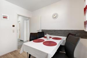 a dining room with a white table and black chairs at Ferienwohnung aufm Weinberg in Schwandorf in Bayern