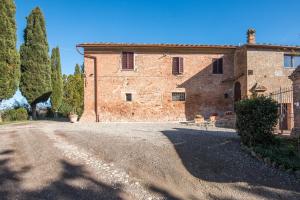 a large brick building with a road in front of it at Casa Al Colle Buonconvento in Buonconvento