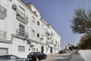 a white building with cars parked on a street at Apartamento en Vejer in Vejer de la Frontera