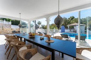 a dining room with a table and chairs and a pool at Holiday Villa Torrenueva in La Cala de Mijas