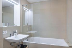 a white bathroom with a sink and a shower at Apartment zum Genießen in Garmisch-Partenkirchen +20 photos
