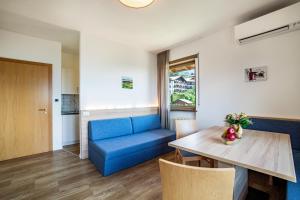 a living room with a blue couch and a table at Gartenheim App Martin in Schenna