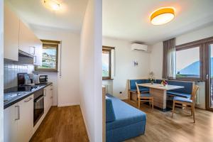 a kitchen and living room with a blue couch and a table at Gartenheim App Martin in Schenna +10 photos
