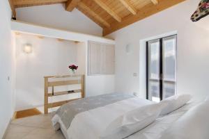 a white bedroom with a bed and a window at Borgo Vico in Verceia
