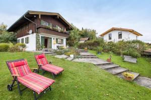 two red chairs sitting in the grass in front of a house at Landhaus Kauderer - Wohnung 2 in Waging am See
