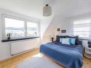 a bedroom with a blue bed and two windows at Dorfhaus1953 in Eslohe