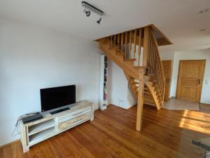 a living room with a staircase and a flat screen tv at Ferienwohnung Dorfprozelten in Dorfprozelten