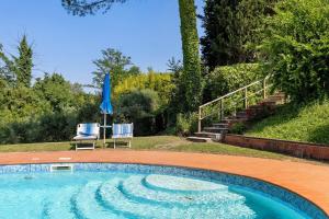 a swimming pool with two chairs and a blue umbrella at La Ripa - Appartamento I Nidi in San Gimignano