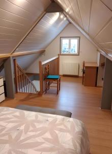 a attic room with a bed and a staircase at Gîte Des Caves in Civray-de-Touraine