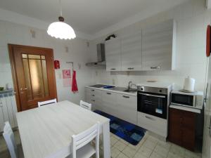 a kitchen with white cabinets and a table and a sink at Casa Delle Gemme in Valenza