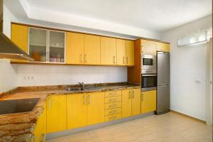 a kitchen with yellow cabinets and stainless steel appliances at Rach Agaete in Agaete