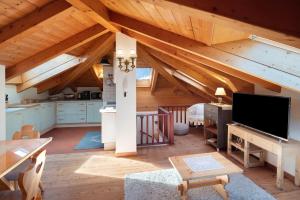 a large living room with wooden ceilings and a flat screen tv at Dimora La Rocca in Daiano