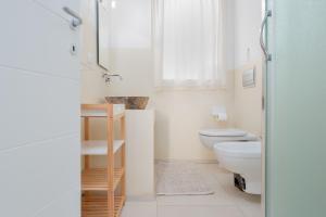 a white bathroom with a toilet and a sink at Cormorani - Appartamento 3 in Golfo Aranci +17 photos